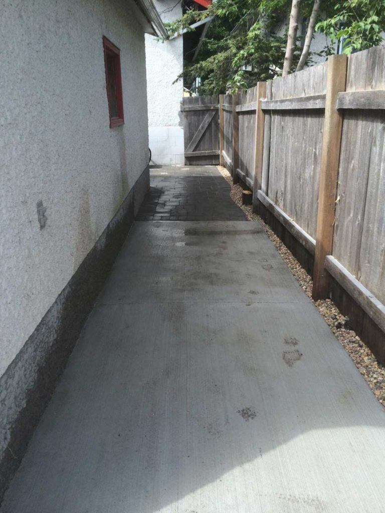 a stone interlock concrete path leading to a residential back yard