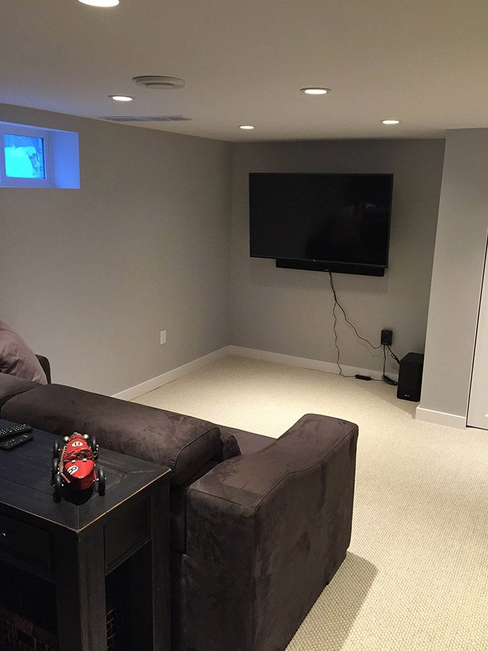 Newly complete basement renovation with a wide screen TV mounted on the wall