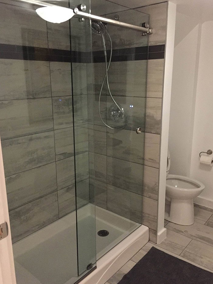 Newly complete basement bathroom renovation with a tile shower stall