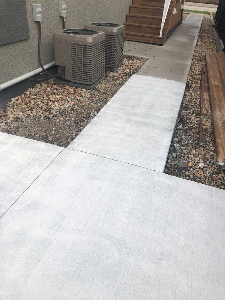 a concrete walkway in the alleyway between residential homes in a city