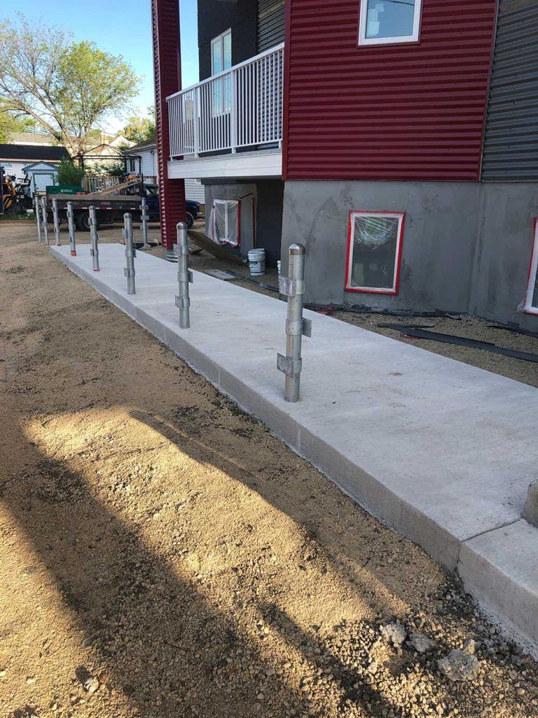 a newly poured concrete walkway in front of a in-progress townhouse development