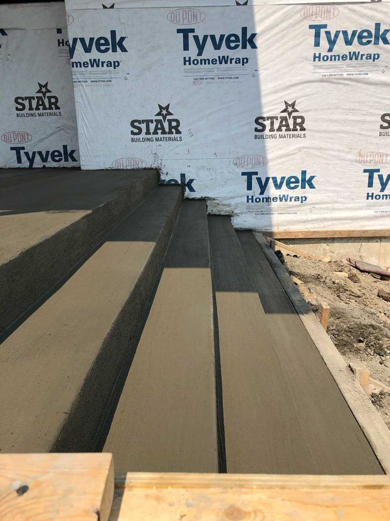 freshly poured concrete steps outside of a new-build house in progress