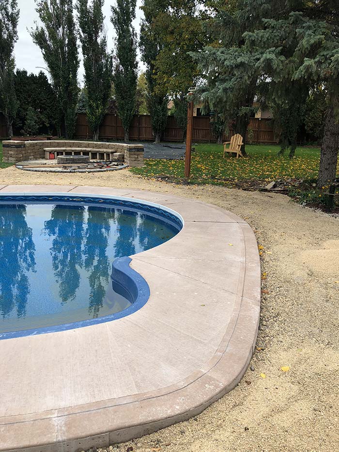 freshly poured new concrete deck beside an in-ground swimming pool